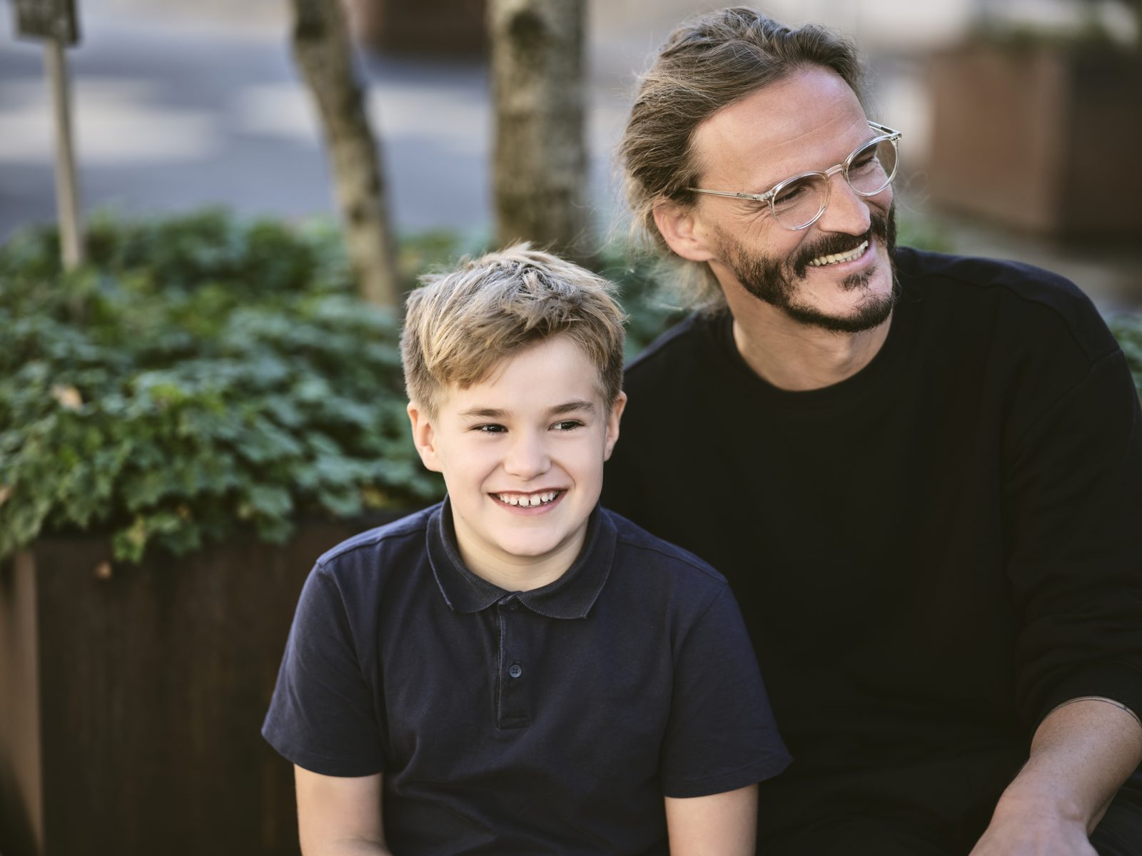 Fröhlicher Bub und Mann sehen zur Seite