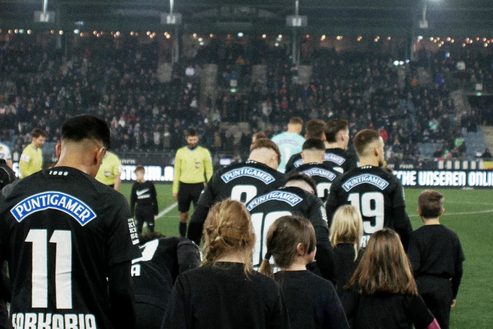 Spieler des SK Sturm Graz laufen mit Kindern in das Stadion ein